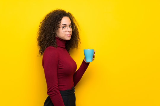 Dominican woman with turtleneck sweater holding a hot cup of coffee