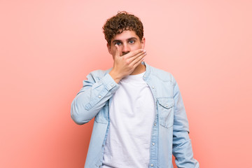 Blonde man over pink wall covering mouth with hands for saying something inappropriate