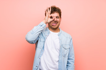 Blonde man over pink wall makes funny and crazy face emotion