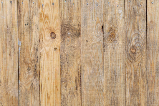 Closeup view of old weathered rustic fence. Wooden background of many vertical planks. Horizontal color photography.