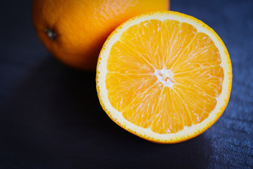 Fresh orange fruit slice half on dark background