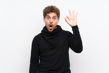 Fototapeta premium Blonde man over isolated white wall surprised and showing ok sign