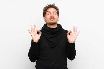 Blonde man over isolated white wall in zen pose