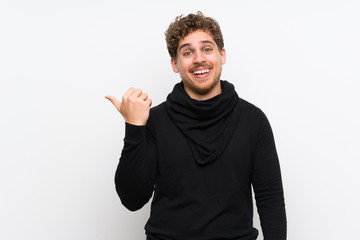 Fototapeta premium Blonde man over isolated white wall pointing to the side to present a product