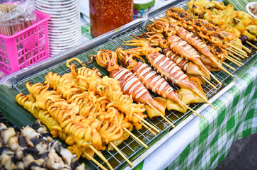 Grilled squid skewer sticks on grill for sale in the street food market asia
