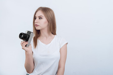 Attractive girl holding a vintage camera in her hands. Looking away