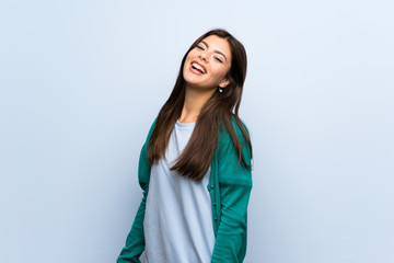 Teenager girl over blue wall smiling