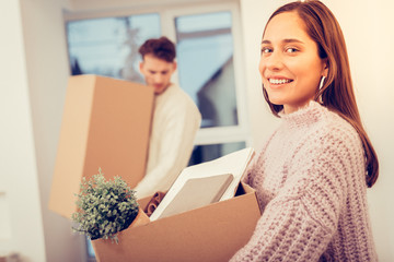 Husband and wife caring boxes with their stuff while moving in bedroom