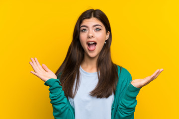 Teenager girl over yellow wall with surprise facial expression