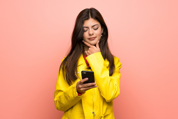 Teenager girl over pink wall thinking and sending a message