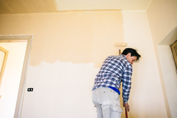 Fototapeta premium husband father of forty years, paints house wall - man painting wall of a room-man performs DIY painting at home