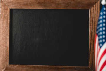 close up of empty black board near american flag