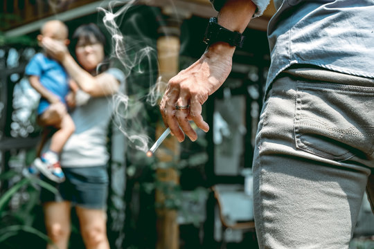 The mother who carries the son scolds the father who holds a cigarette that smells smoke.