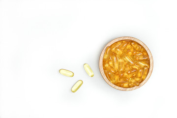 Top view close up of fish oil capsules in bowl wooden on white background. Omega 3. Vitamin E. Supplementary food background.