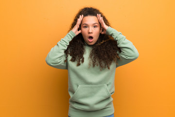 Teenager girl over ocher wall with surprise expression