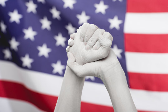 cropped view of female clenched hands painted in white near american flag