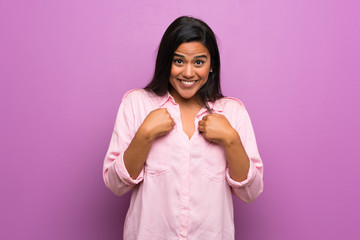 Young Colombian girl over purple wall with surprise facial expression