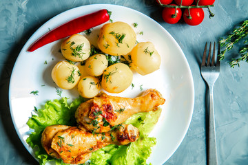 Chicken legs with potatoes and vegetables.