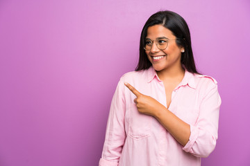 Fototapeta premium Young Colombian girl over purple wall pointing finger to the side