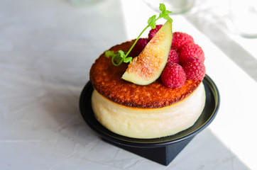 Creamy New York style Cheesecake with berry topping. Example of elegant foodstyling with fruits, fig, raspberry and mint.