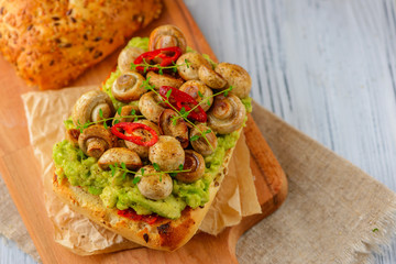 Smashed avocado, mushrooms and chili pepper whole grain sandwich. Decorated with thyme