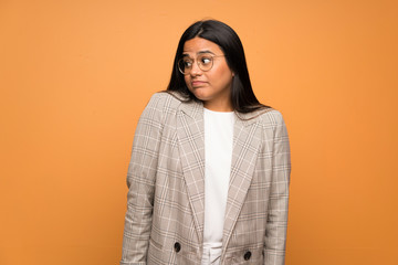 Young Colombian girl over brown wall making doubts gesture looking side