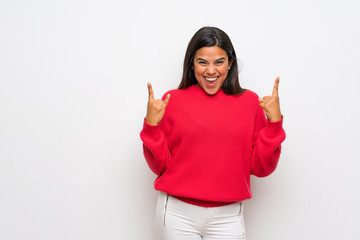 Young Colombian girl with red sweater making rock gesture