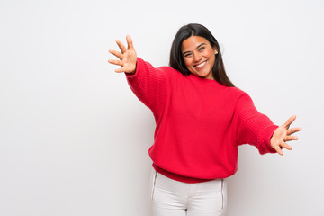 Young Colombian girl with red sweater presenting and inviting to come with hand