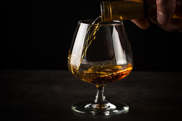 Pouring brandy or cognac in the glass.