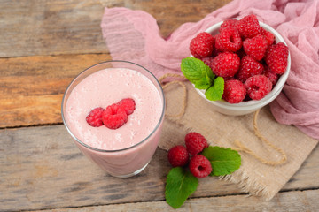 Glass of raspberry milk shake with berries on wooden background