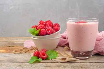 Glass of raspberry milk shake with berries on wooden background