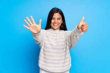 Young Colombian girl with sweater counting six with fingers