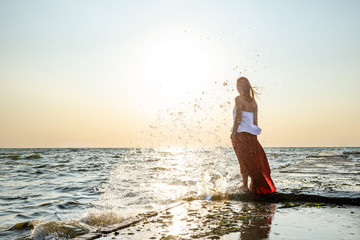 Beautiful girl in red dress by the sea.