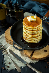 Pancakes with butter in the black pan. Decorated with tablecloth on a dark background