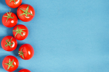 Bright organic tomatoes on a blue background, copy space. - Image