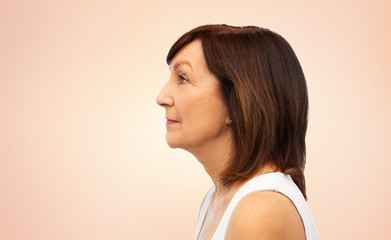 beauty, rhinoplasty and old people concept - profile of senior woman over beige background