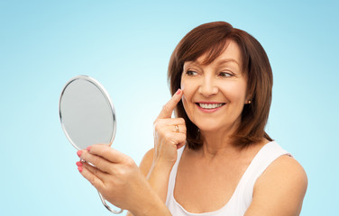 beauty and old people concept - portrait of smiling senior woman with mirror touching her face over...