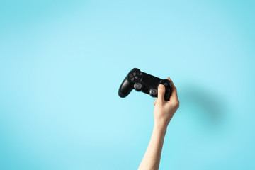 Black joystick in hands isolated on bright blue background