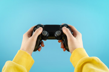  Black joystick in hands isolated on pastel blue background © brizmaker