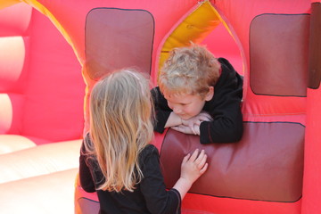 Portrait of little boy and girl on a bouncy castle