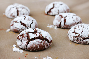Chocolate cookies with cracks on baking paper and iolated on black. Cracked chocolate biscuits