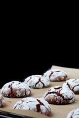 Chocolate cookies with cracks on baking paper and iolated on black. Cracked chocolate biscuits