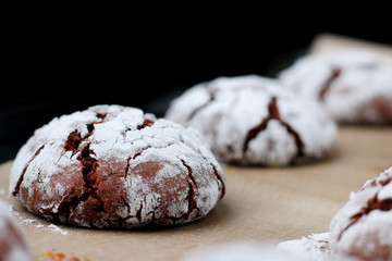 Chocolate cookies with cracks on baking paper and iolated on black. Cracked chocolate biscuits