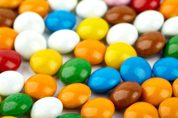 colorful candy on white background. Rainbow sprinkles for topping ice cream and cake. Small candies in colored chocolate glaze.