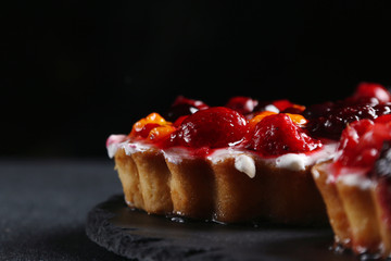 tart with berries on dark background. pie with raspberries and many berries