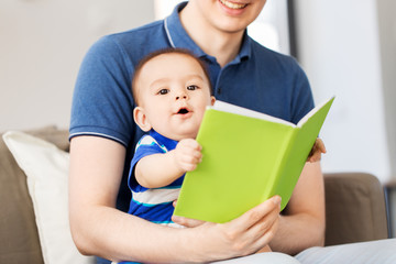 family, parenthood and people concept - happy father and little baby son with book at home