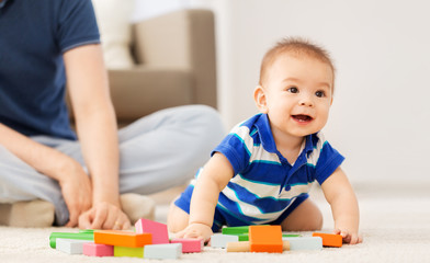 family, fatherhood and childhood concept - baby boy and father playing with toy blocks at home