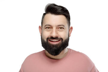 A cute young bearded man in pink shirt shows emotionally happy