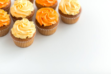 food, pastry and confectionery concept - cupcakes with buttercream frosting over white background
