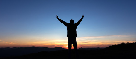 Victoire d'un homme au sommet d'une montagne au coucher de soleil
